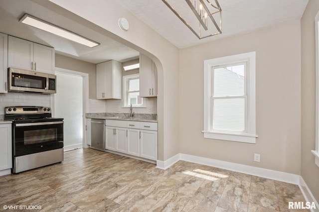 2428 S 8th St, Springfield, IL 62703 - kitchen with appliances with stainless steel finishes, backsplash, white cabinets, baseboards, and light stone countertops