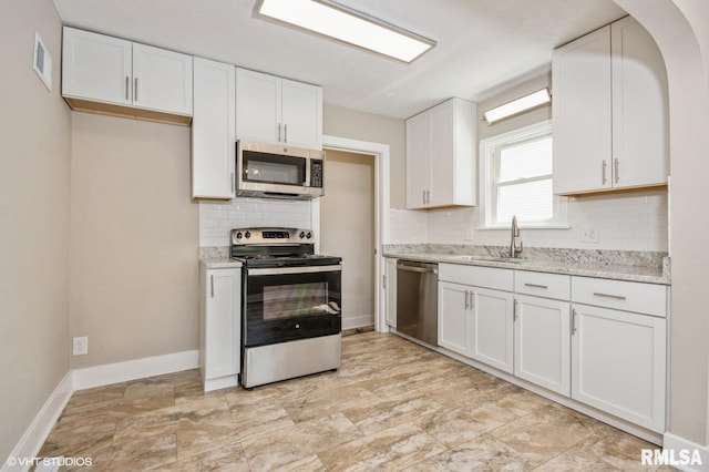 2428 S 8th St, Springfield, IL 62703 - kitchen featuring appliances with stainless steel finishes, a sink, backsplash, white cabinetry, and baseboards
