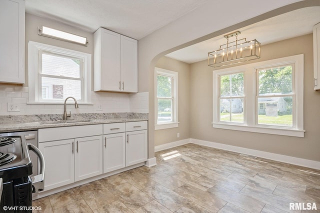 2428 S 8th St, Springfield, IL 62703 - kitchen with arched walkways, tasteful backsplash, a sink, white cabinets, and baseboards