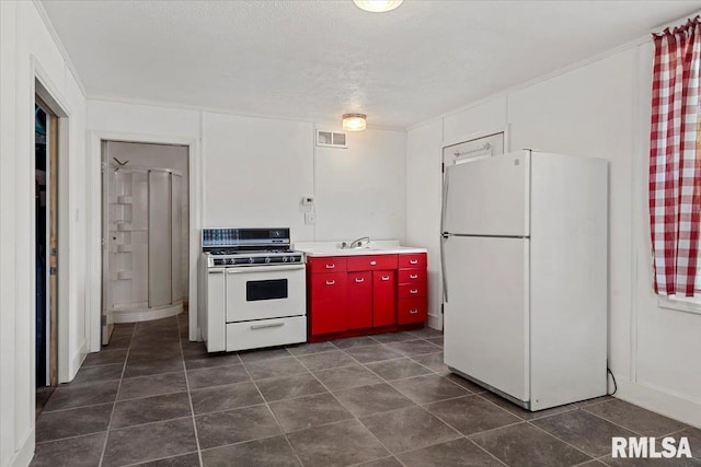 4101 N 8th St, Springfield, IL 62707 - kitchen with white appliances, red cabinetry, a sink, and dark tile patterned flooring