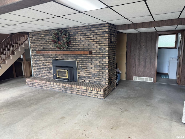 18382 N Quiver Beach Rd, Havana, IL 62644 - unfurnished living room with concrete floors, a paneled ceiling, stairway, and wooden walls