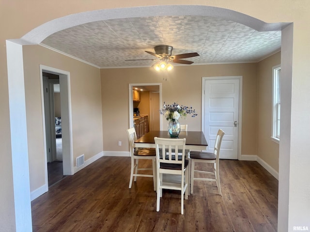 1106 S 19th St, Quincy, IL 62301 - dining area featuring dark wood finished floors, crown molding, baseboards, arched walkways, and a ceiling fan