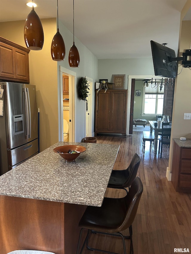 118 W Clark St, Havana, IL 62644 - kitchen with stainless steel fridge with ice dispenser, dark wood-type flooring, a breakfast bar area, a center island, and brown cabinets