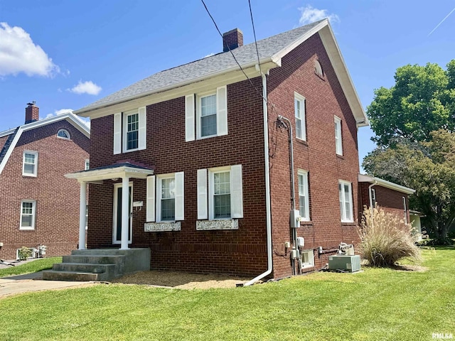 1595 N Kellogg St, Galesburg, IL 61401 - view of front of property with a chimney, a front lawn, brick siding, and central AC