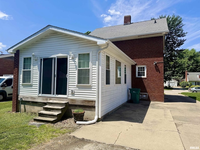 1595 N Kellogg St, Galesburg, IL 61401 - view of home's exterior with entry steps, a chimney, brick siding, and a shingled roof