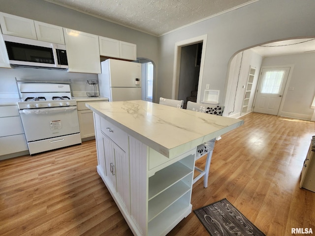228 4th St, Lincoln, IL 62656 - kitchen with white appliances, arched walkways, white cabinetry, light countertops, and a textured ceiling