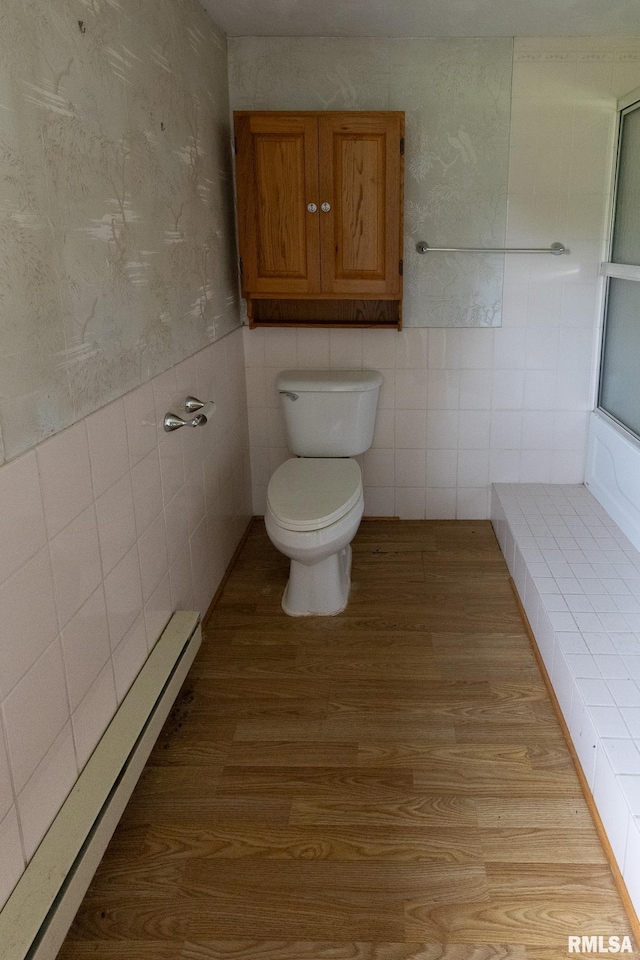 30 Ryder St, Nilwood, IL 62672 - bathroom with tile walls, toilet, wood finished floors, a baseboard heating unit, and wallpapered walls