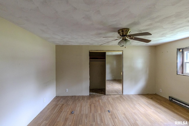 30 Ryder St, Nilwood, IL 62672 - unfurnished bedroom with a baseboard radiator, wood finished floors, a closet, a ceiling fan, and a textured ceiling