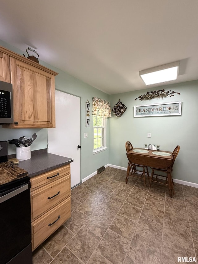 709 W Monmouth St, Abingdon, IL 61410 - kitchen with black range with electric stovetop, stainless steel microwave, dark countertops, and baseboards