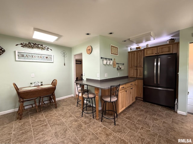 709 W Monmouth St, Abingdon, IL 61410 - kitchen with freestanding refrigerator, dark countertops, baseboards, a breakfast bar, and a peninsula