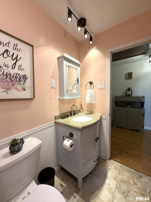 709 W Monmouth St, Abingdon, IL 61410 - half bath featuring vanity, toilet, wainscoting, and stone finish flooring