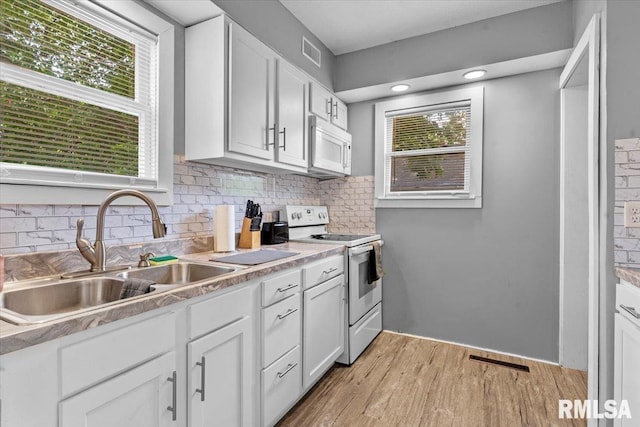 2557 S 6th St, Springfield, IL 62703 - kitchen with white appliances, a sink, decorative backsplash, light wood finished floors, and white cabinetry