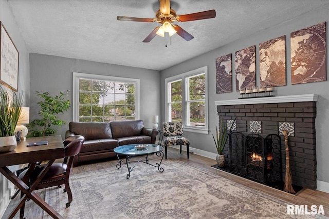 2557 S 6th St, Springfield, IL 62703 - living area featuring wood finished floors, a textured ceiling, a fireplace, healthy amount of natural light, and a ceiling fan