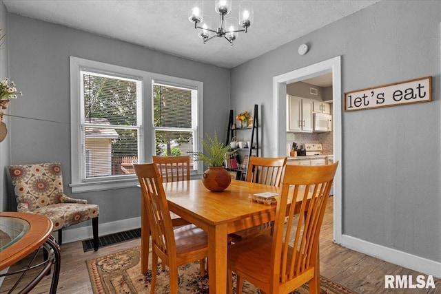 2557 S 6th St, Springfield, IL 62703 - dining area featuring baseboards, light wood finished floors, a chandelier, plenty of natural light, and a textured ceiling