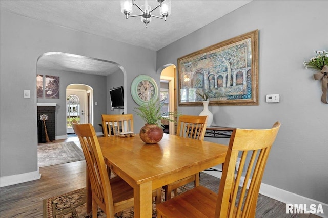 2557 S 6th St, Springfield, IL 62703 - dining room featuring arched walkways, baseboards, a brick fireplace, wood finished floors, and a textured ceiling