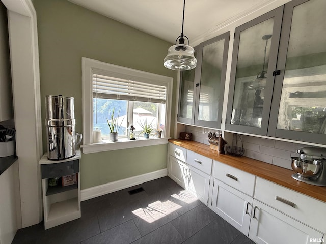 344 S 24th St, Quincy, IL 62301 - kitchen featuring butcher block countertops, tasteful backsplash, dark tile patterned flooring, baseboards, and white cabinetry