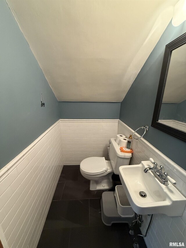 344 S 24th St, Quincy, IL 62301 - bathroom with toilet, wainscoting, tile walls, vaulted ceiling, and a sink