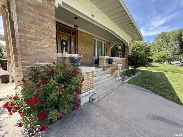 344 S 24th St, Quincy, IL 62301 - view of exterior entry featuring a porch, brick siding, and a lawn