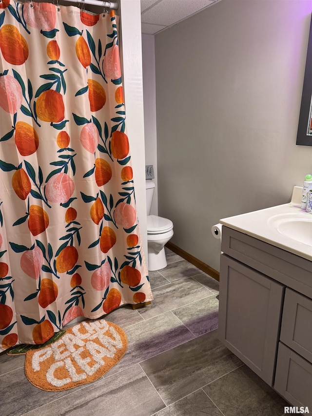 409 N Broadway St, Havana, IL 62644 - bathroom featuring vanity, toilet, a paneled ceiling, a shower with shower curtain, and baseboards