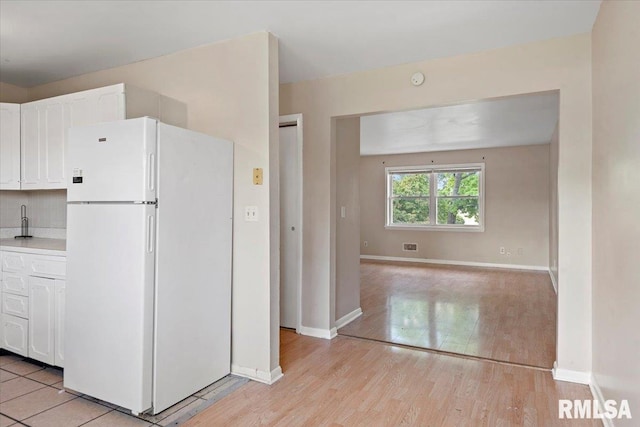2309 W Lawrence Ave, Springfield, IL 62704 - kitchen with freestanding refrigerator, white cabinetry, light countertops, light wood finished floors, and baseboards