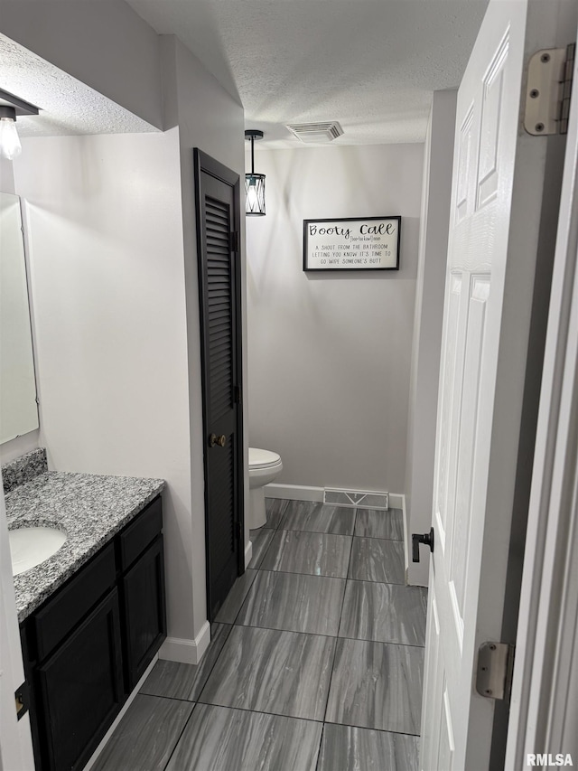 1352 N Lawrence Ave, Taylorville, IL 62568 - bathroom with vanity, a textured ceiling, a closet, toilet, and baseboards
