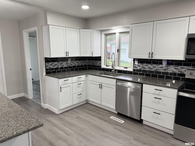 1352 N Lawrence Ave, Taylorville, IL 62568 - kitchen featuring appliances with stainless steel finishes, a sink, white cabinetry, light wood-style floors, and decorative backsplash