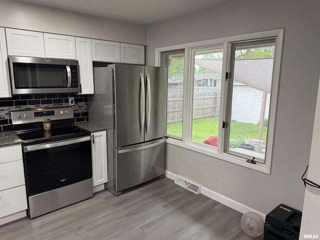 1352 N Lawrence Ave, Taylorville, IL 62568 - kitchen with stainless steel appliances, white cabinetry, light wood-style flooring, backsplash, and dark stone counters
