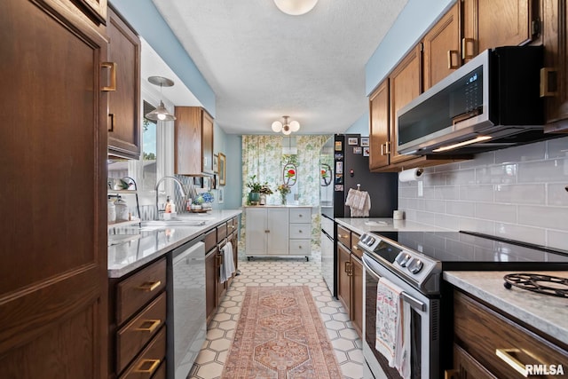 704 Rickard Rd, Springfield, IL 62704 - kitchen with appliances with stainless steel finishes, a sink, a textured ceiling, light countertops, and decorative backsplash