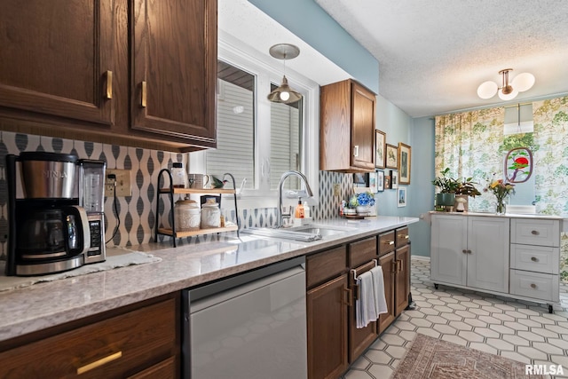 704 Rickard Rd, Springfield, IL 62704 - kitchen with stainless steel dishwasher, a sink, light stone countertops, a textured ceiling, and pendant lighting