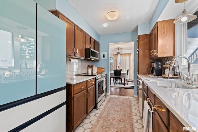 704 Rickard Rd, Springfield, IL 62704 - kitchen with stainless steel appliances, a sink, light countertops, decorative backsplash, and pendant lighting