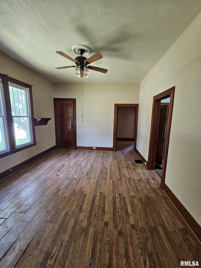 216 W Church St, Palmyra, MO 63461 - unfurnished living room featuring dark wood-type flooring, a textured ceiling, and a ceiling fan