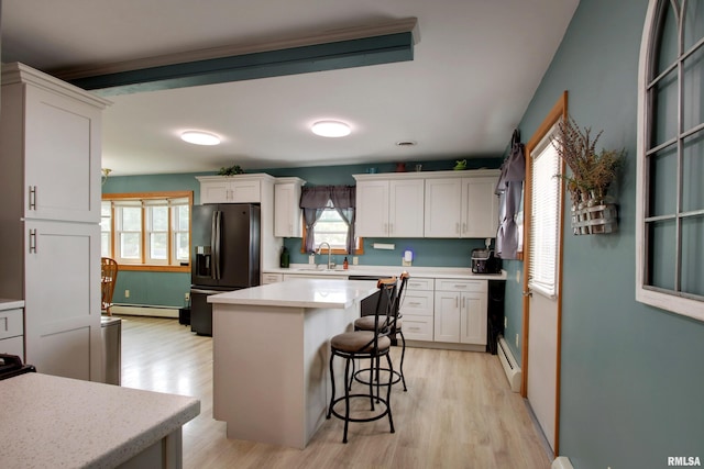 130 S State St, Mendon, IL 62351 - kitchen featuring baseboard heating, black fridge with ice dispenser, a sink, a baseboard heating unit, and light wood-style floors