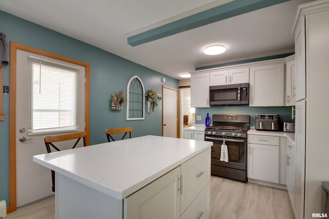 130 S State St, Mendon, IL 62351 - kitchen with stainless steel appliances, light countertops, light wood-style floors, a center island, and white cabinetry