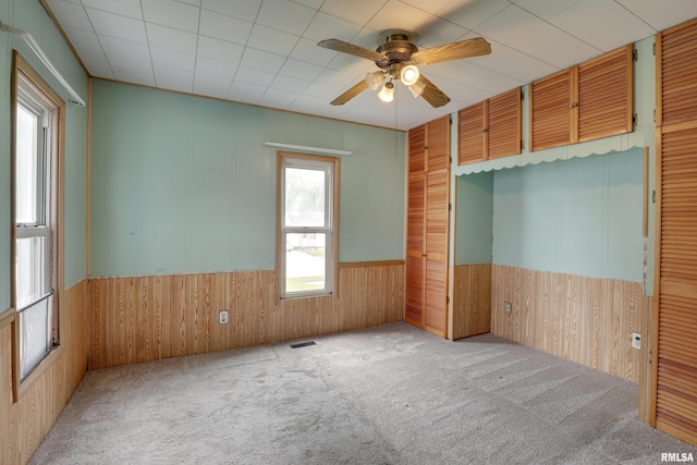 2911 Hampshire St, Quincy, IL 62301 - carpeted empty room with ceiling fan, a wainscoted wall, and wooden walls