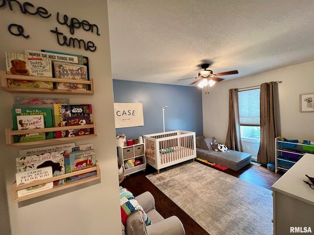 409 W Main St, Williamsville, IL 62693 - bedroom featuring a textured ceiling, dark wood finished floors, a crib, and a ceiling fan