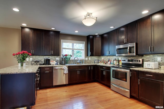 507 W Fairway Dr, Quincy, IL 62305 - kitchen with appliances with stainless steel finishes, a sink, light wood finished floors, light stone countertops, and tasteful backsplash