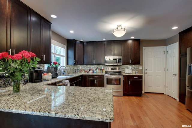 507 W Fairway Dr, Quincy, IL 62305 - kitchen featuring appliances with stainless steel finishes, a sink, light stone countertops, dark brown cabinetry, and light wood-type flooring