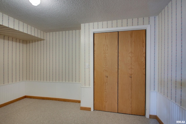 2044 N 1200th Ave, Liberty, IL 62347 - unfurnished bedroom with wallpapered walls, a textured ceiling, wainscoting, carpet flooring, and a closet