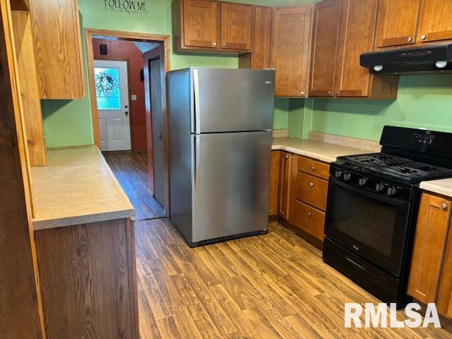505 E Elm St, Carlinville, IL 62626 - kitchen with freestanding refrigerator, black range with gas stovetop, extractor fan, wood finished floors, and light countertops