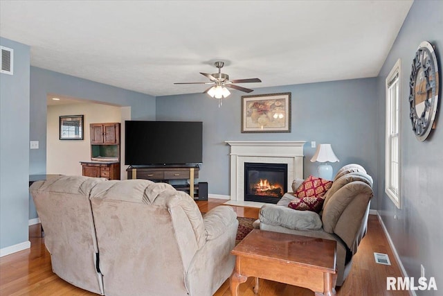 4108 Newtonmore Dr, Springfield, IL 62712 - living room featuring wood finished floors, baseboards, a ceiling fan, and a fireplace with flush hearth