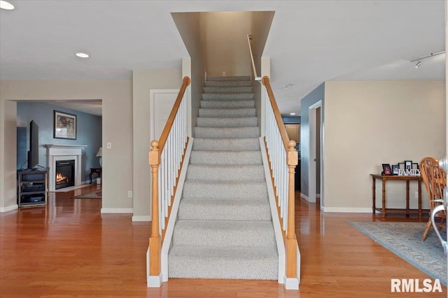 4108 Newtonmore Dr, Springfield, IL 62712 - stairs featuring wood finished floors, baseboards, a warm lit fireplace, and recessed lighting