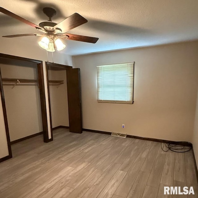 504 W Chestnut St, Chatham, IL 62629 - unfurnished bedroom featuring light wood-style floors, multiple closets, baseboards, ceiling fan, and a textured ceiling