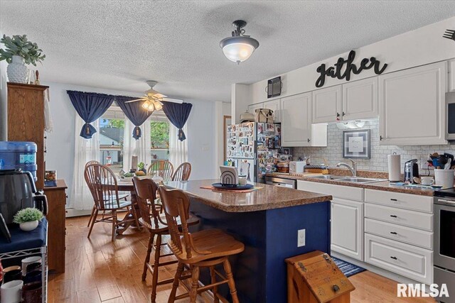 122 W Chapin St, Litchfield, IL 62056 - kitchen with a sink, appliances with stainless steel finishes, a textured ceiling, a center island, and white cabinetry