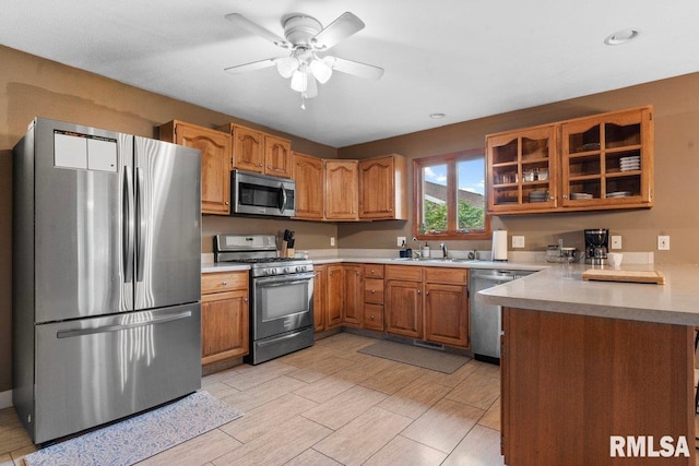 136 Lilac Ln, Chatham, IL 62629 - kitchen featuring stainless steel appliances, a sink, brown cabinetry, light countertops, and glass insert cabinets