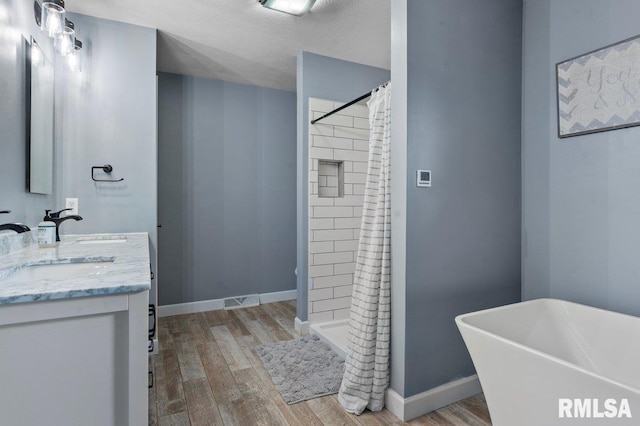 136 Lilac Ln, Chatham, IL 62629 - bathroom featuring wood finished floors, double vanity, a stall shower, and a freestanding tub