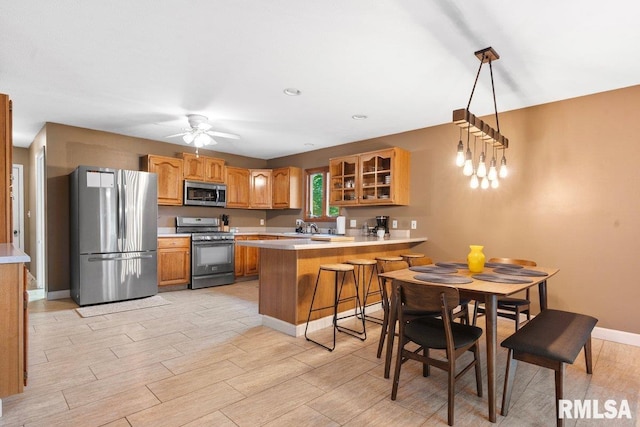 136 Lilac Ln, Chatham, IL 62629 - kitchen featuring appliances with stainless steel finishes, a peninsula, glass insert cabinets, light countertops, and brown cabinets