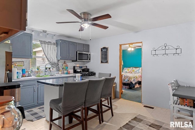 417 W Franklin St, Girard, IL 62640 - kitchen featuring stainless steel microwave, range with gas cooktop, a sink, ceiling fan, and gray cabinets