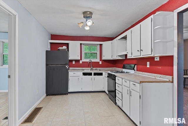 417 W Franklin St, Girard, IL 62640 - kitchen featuring freestanding refrigerator, range with gas stovetop, open shelves, a sink, and white cabinetry