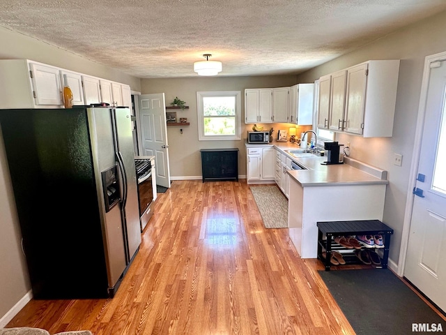 2900 Old State Rd, Alexander, IL 62601 - kitchen featuring appliances with stainless steel finishes, light wood-style flooring, light countertops, a textured ceiling, and white cabinets