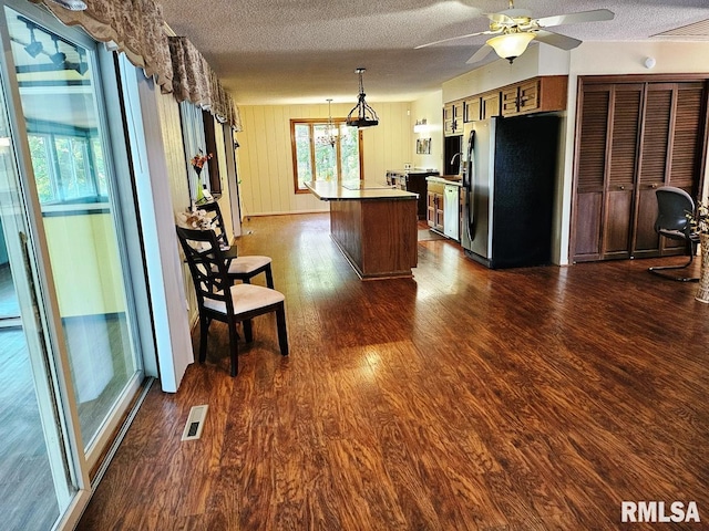 12862 Winnebago Dr, Plainview, IL 62685 - kitchen with stainless steel refrigerator with ice dispenser, dark wood-type flooring, a textured ceiling, ceiling fan, and a kitchen island